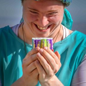 girl holding assortment of lip gloss and smiling