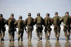 paratroopers on the beach walking away from you in a line